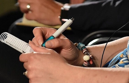 person writing in handbook